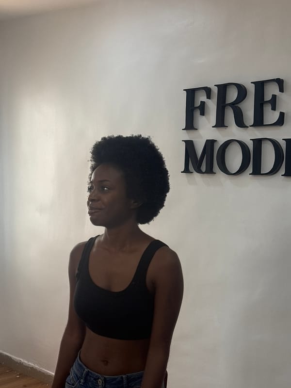 Woman poses by 'FREE MOD' wall sign in Lagos
