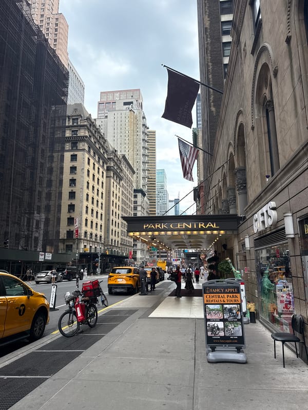 Midtown sidewalk: cabs, tourists traps, and a mini Lady Liberty