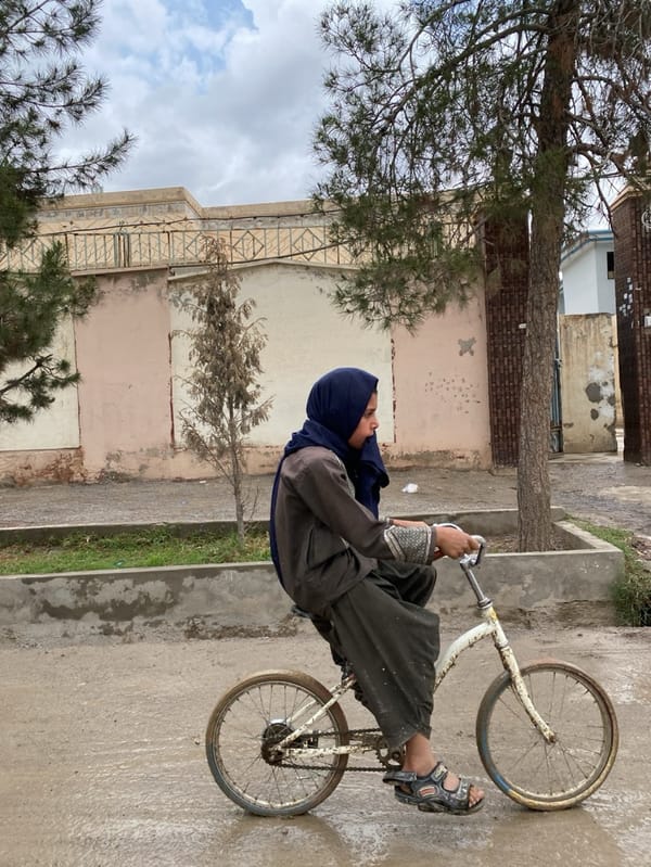 Young cyclist spotted on wet Kandahar street