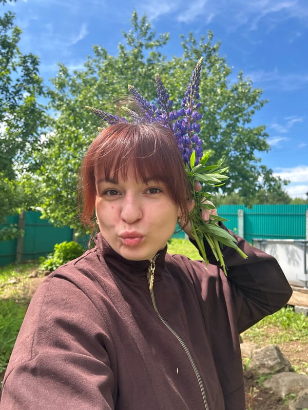 Woman poses with purple lupine bouquet in Russian countryside