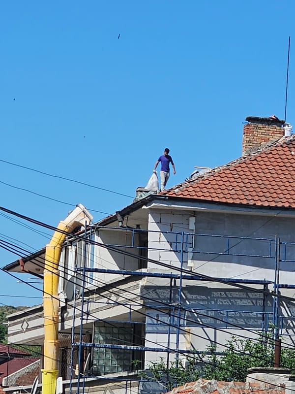 Man walks on rooftop edge during construction in Karnobat