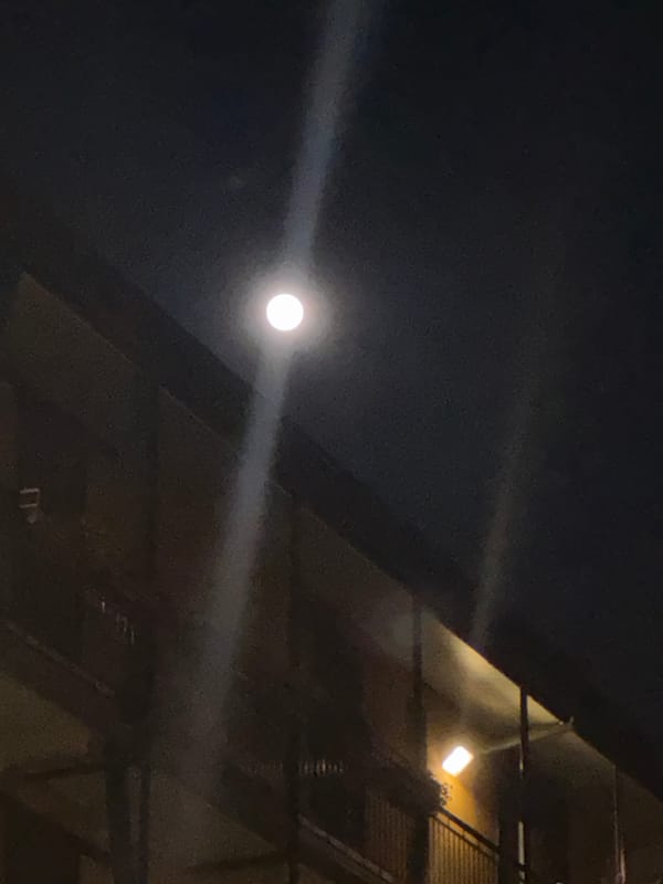 Bright moon illuminates Milan skyline with striking light-ray effect