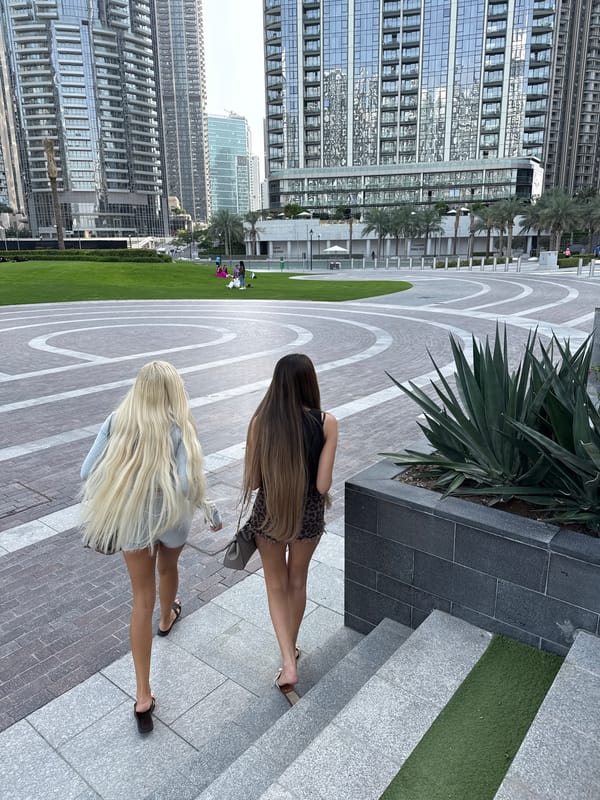 Women walk near Dubai pool with skyline views