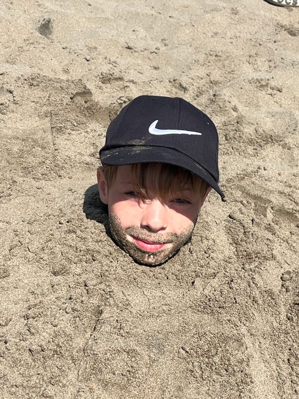 Kids bury a friend in sand on a Siberian beach
