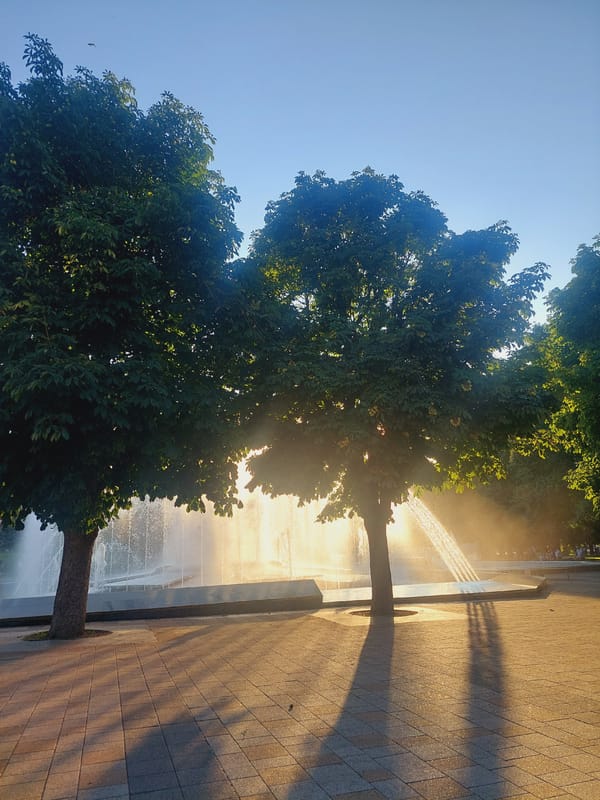 Fountain plaza at dusk, beside a striped domed church