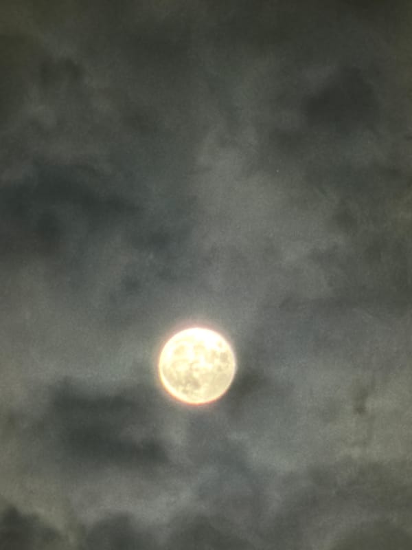 Full moon visible through cloudy night sky over Varna