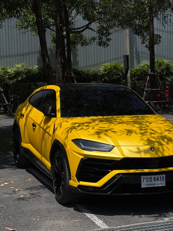 Yellow Lamborghini Urus parked outside industrial building in Si Sunthon