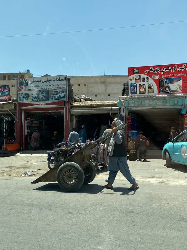 Man pulls cart with metal goods through Kandahar street