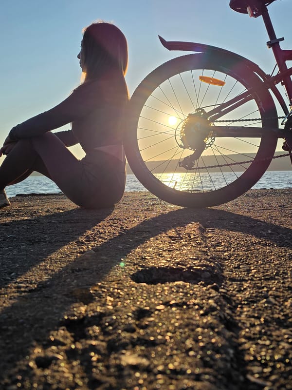 Woman with bicycle enjoys sunset by Kama River in Chaikovsky