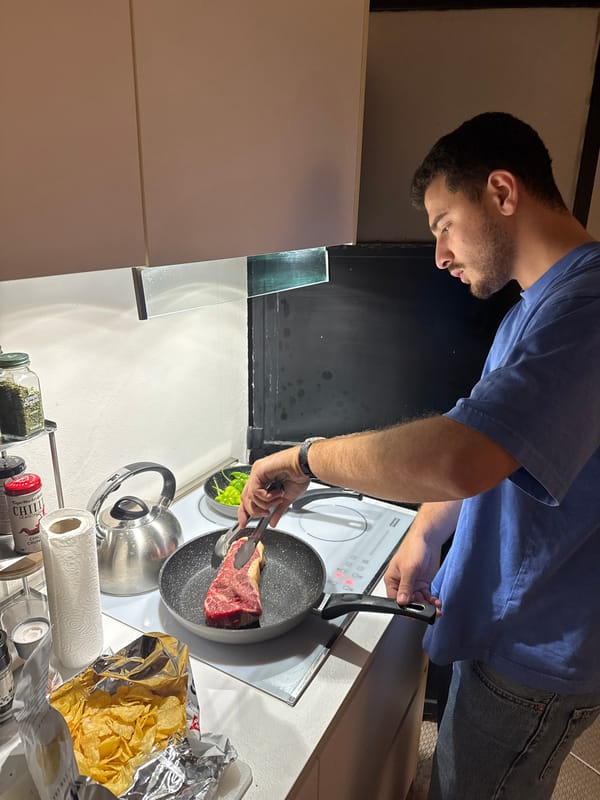 Young man cooks steak dinner in Milan kitchen