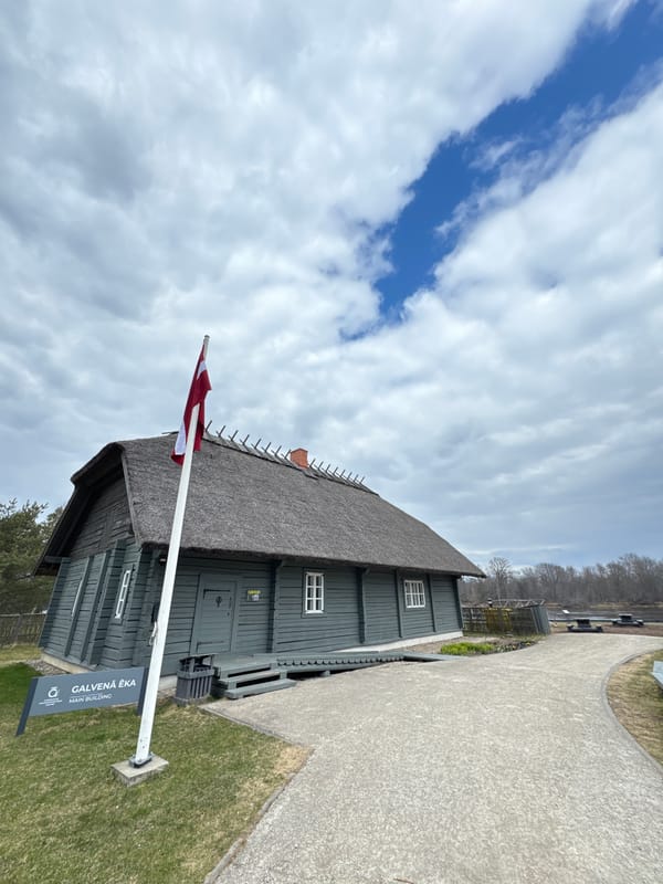 Traditional thatched building with Latvian flag observed in Carnikava