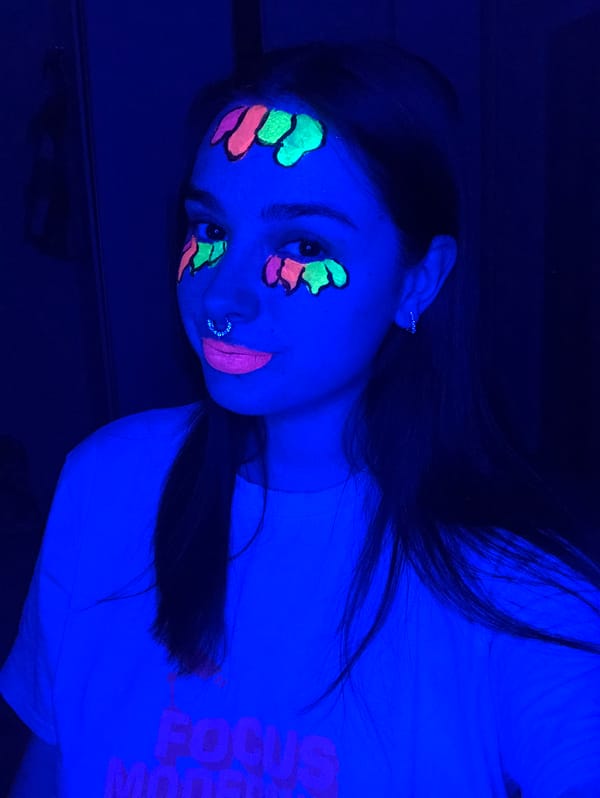 Woman documents blacklight face painting session in Noviy, Russia