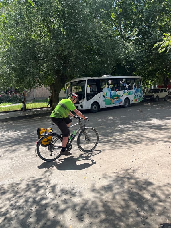 Cyclist and parked gold Nissan on a quiet urban street