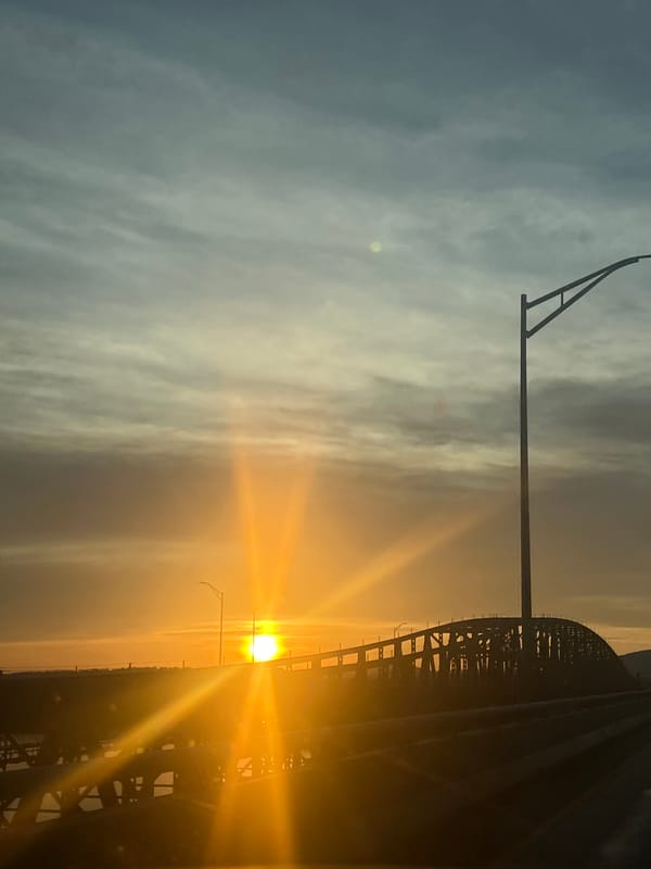 Sunset traffic observed on Newburgh bridge amid colorful sky