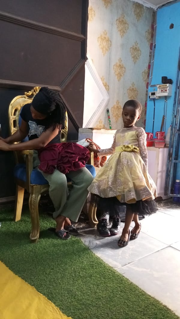 Woman helps dress children in Sabon Tasha home setting