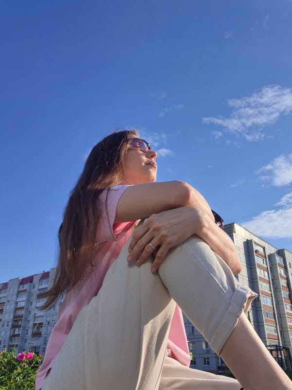 Woman in pink shirt sits outdoors in casual afternoon moment
