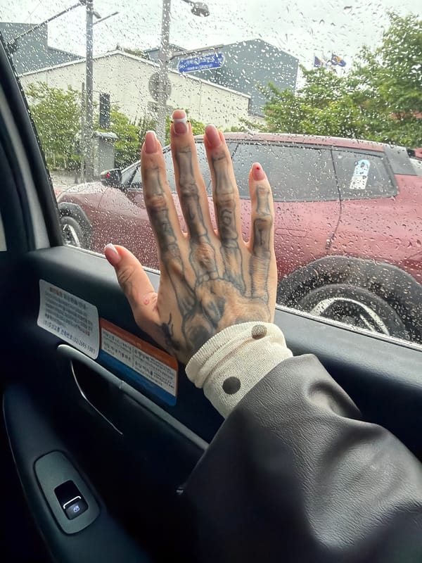 Tattooed hand reaches for rainy car window in Gimpo