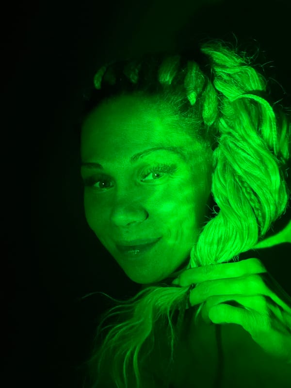 Green-lit portrait captured showing braided subject with neutral expression