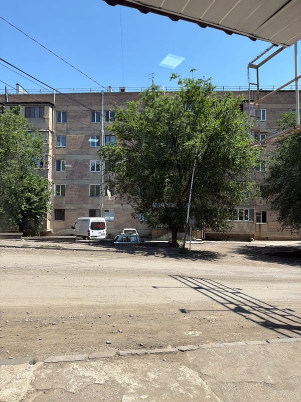 Street view of a light stone apartment building with open windows
