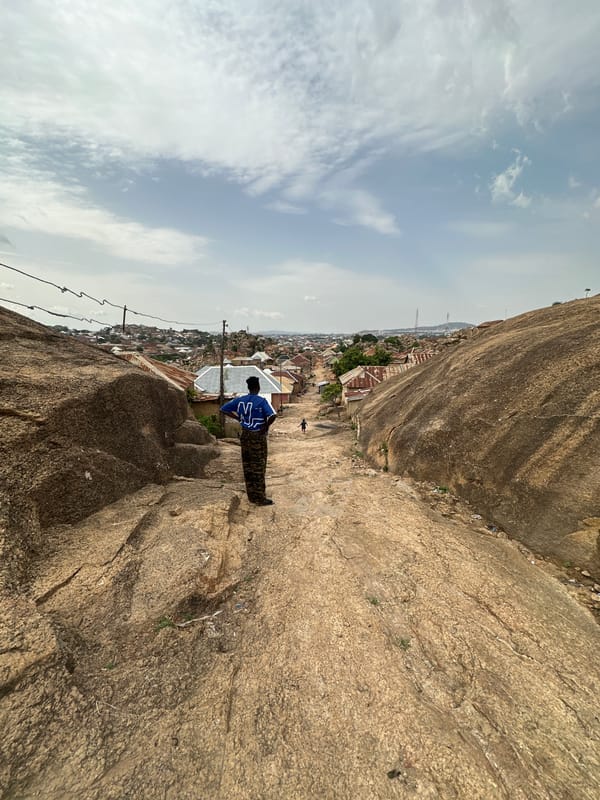 Person in camouflage overlooks Jos from rocky cliff