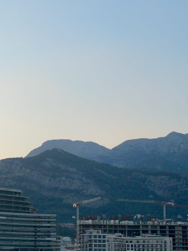 Waterfront city at dusk: construction, fishing, and a crescent moon