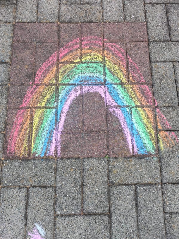Chalk rainbow artwork spotted on outdoor paving stones