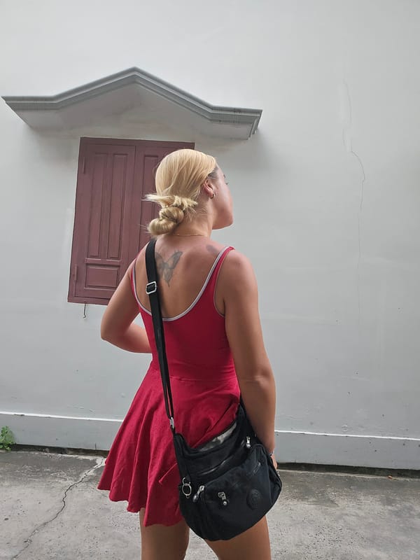 Butterfly tattoo and red dress against a white wall in Vietnam