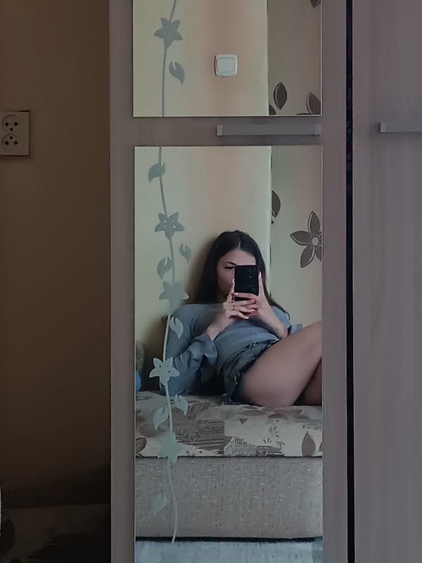 Mirror selfie on a patterned bench, casual outfit.