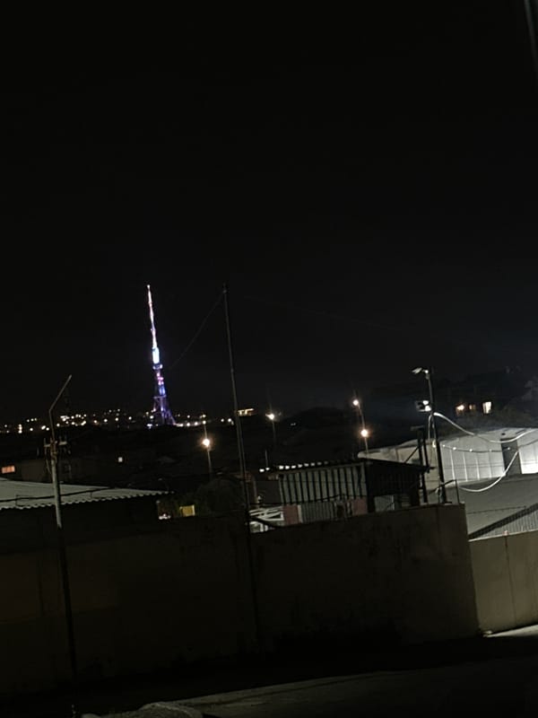 Nighttime urban documentation captures illuminated tower, vehicles, buildings