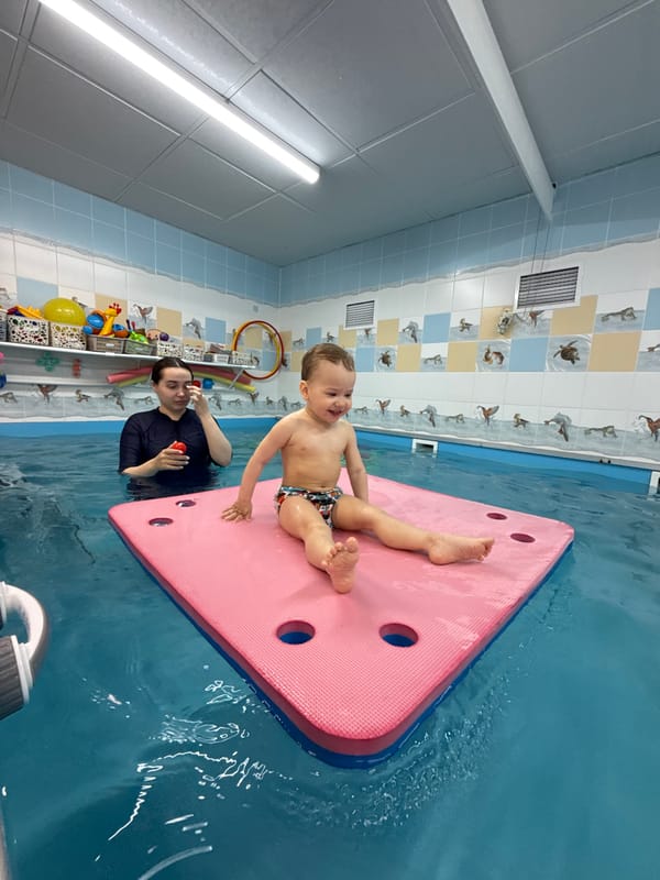 Toddler enjoys swimming activities on pink float in Rusanovo pool