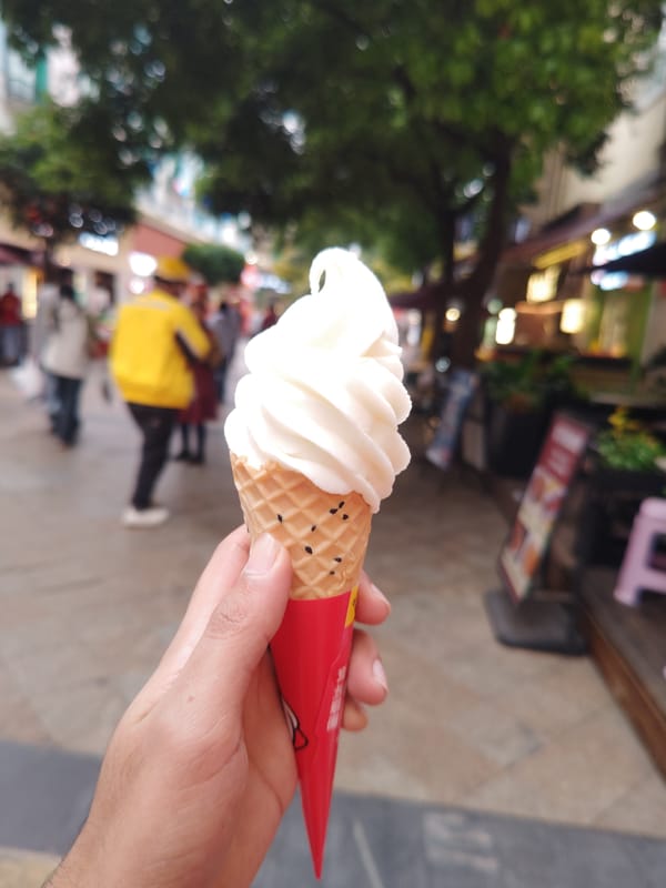 Person enjoys soft-serve ice cream on busy Chinese street