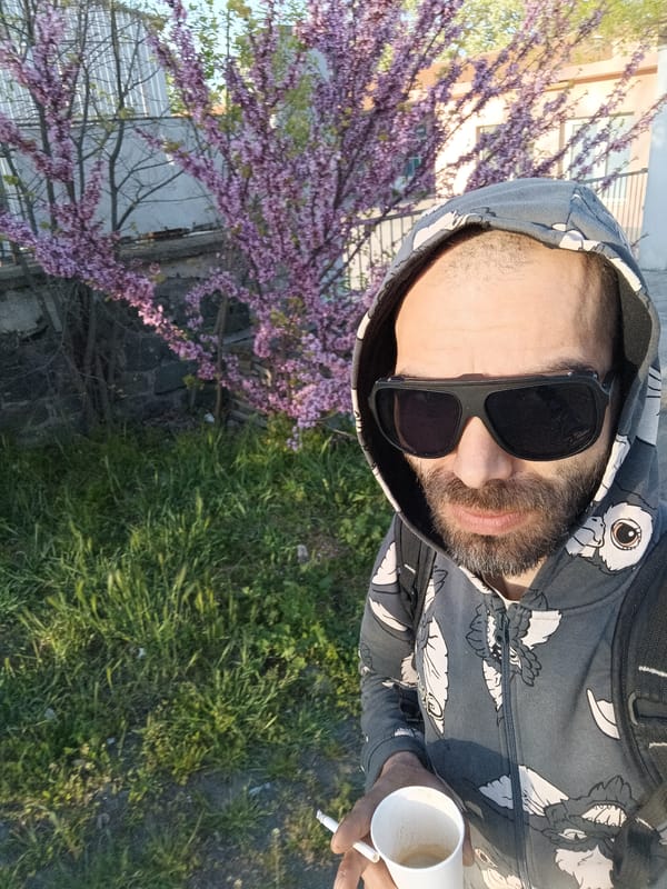 Man takes outdoor selfie with coffee and cigarette