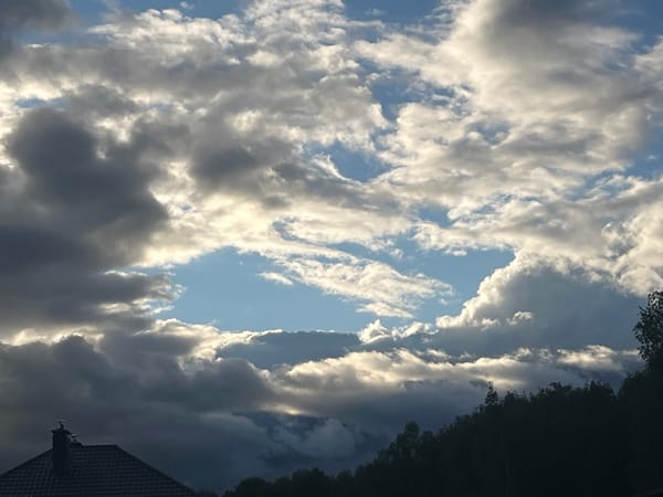 Partly cloudy skies with contrail observed over residential area