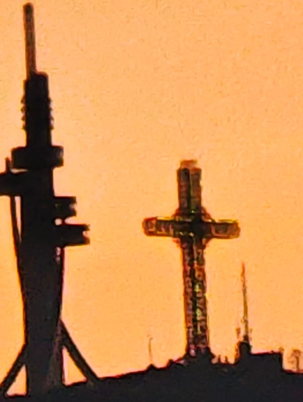 Sunset silhouettes telecommunications tower and cross in Skopje