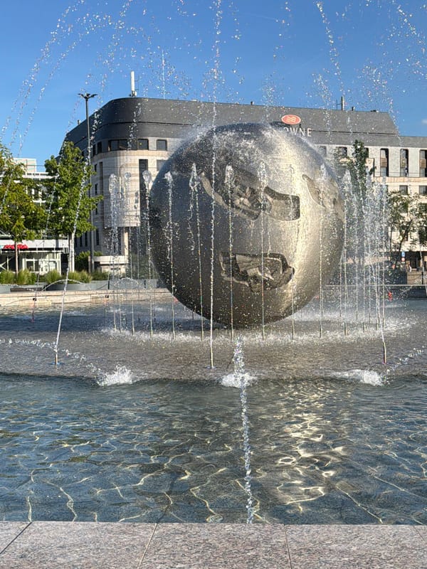 Street musician performs near fountain as child plays nearby