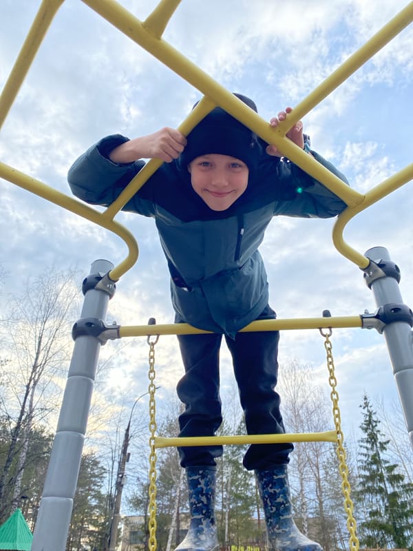 Child plays on playground equipment near Ferris wheel in Chaikovsky