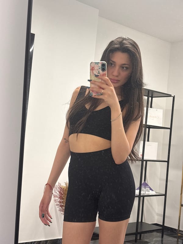 Woman takes mirror selfies in athletic wear, displays tattoo