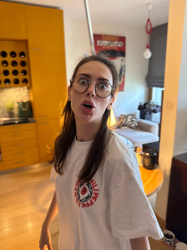 Woman in white shirt captured across kitchen and workspace
