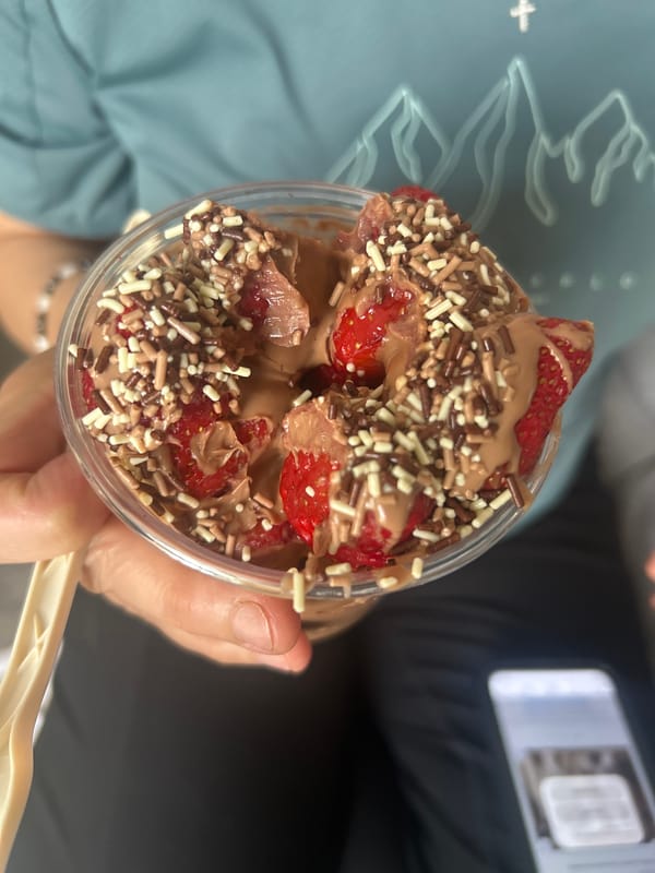 Person holds strawberry chocolate dessert cup with sprinkles