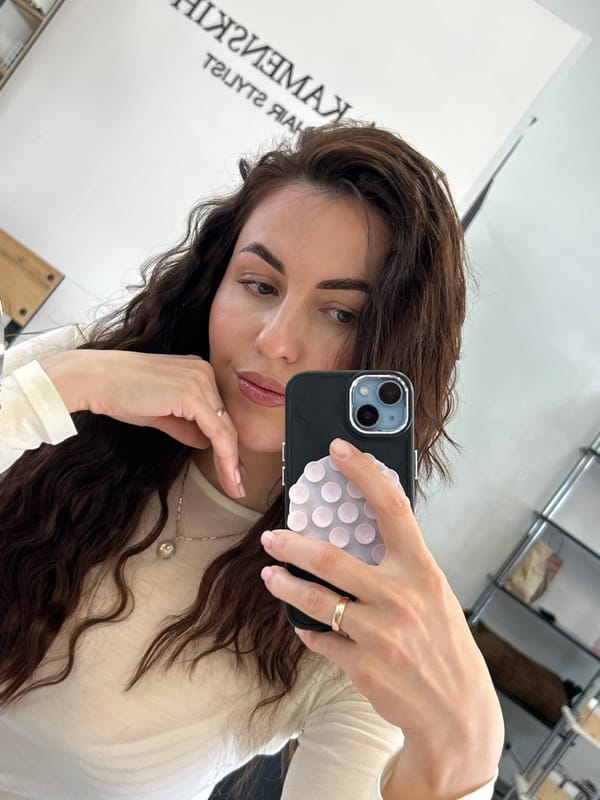 Woman takes selfie with decorated phone in indoor setting