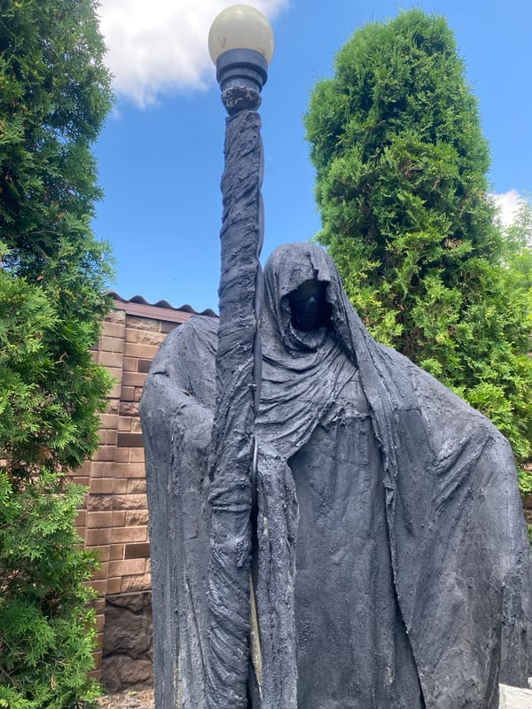 Garden details: statues, flowers, fountain, and a scarecrow figure