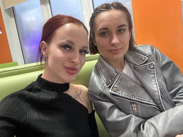 Two women pose for photos indoors in Simferopol