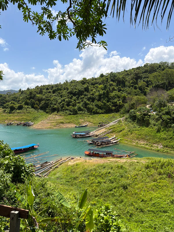 Longtail boats rest on turquoise Cheow Lan Lake, Thailand.