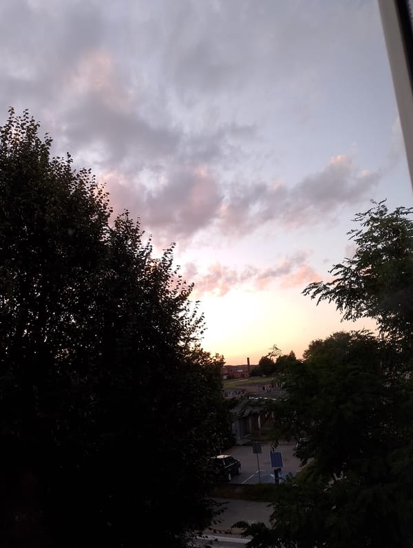 Suburban dusk sky, clouds lit orange and pink at sunset