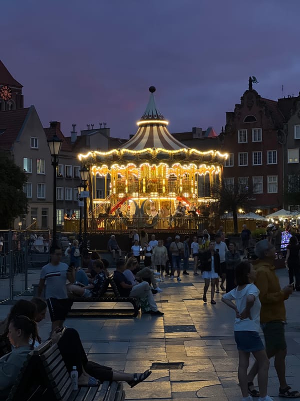 Lit carousel and evening foot traffic in Gdańsk's old town
