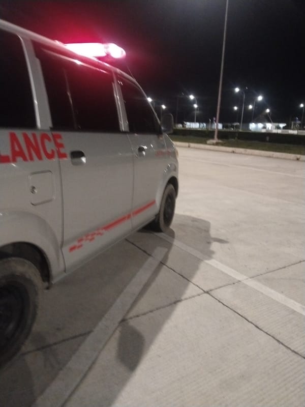 Emergency ambulance parked with lights active in Indonesian parking lot