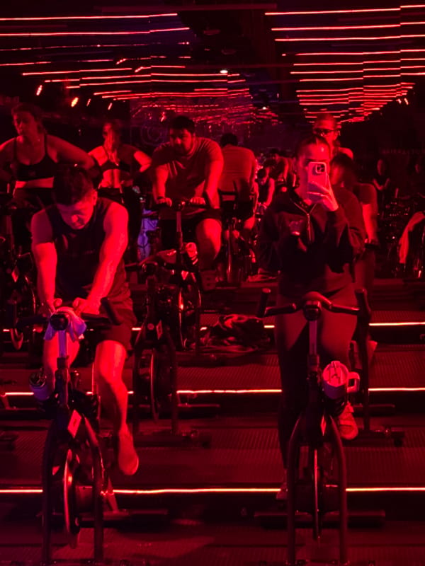 Indoor cycling class under red neon lights in Puebla