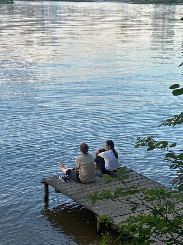 Two people sit on wooden dock in Moscow waterway