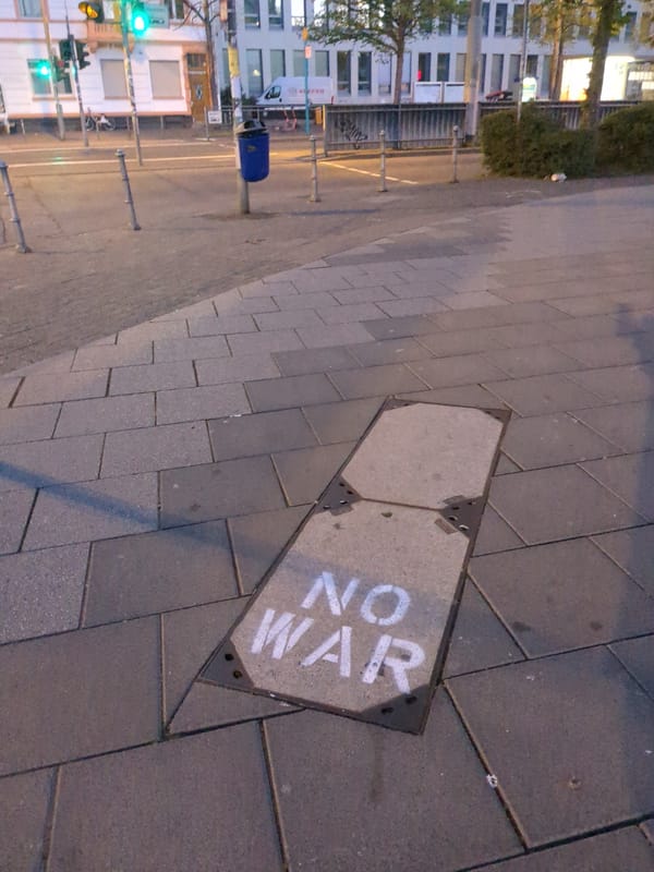 Anti-war graffiti spotted on sidewalk metal plate