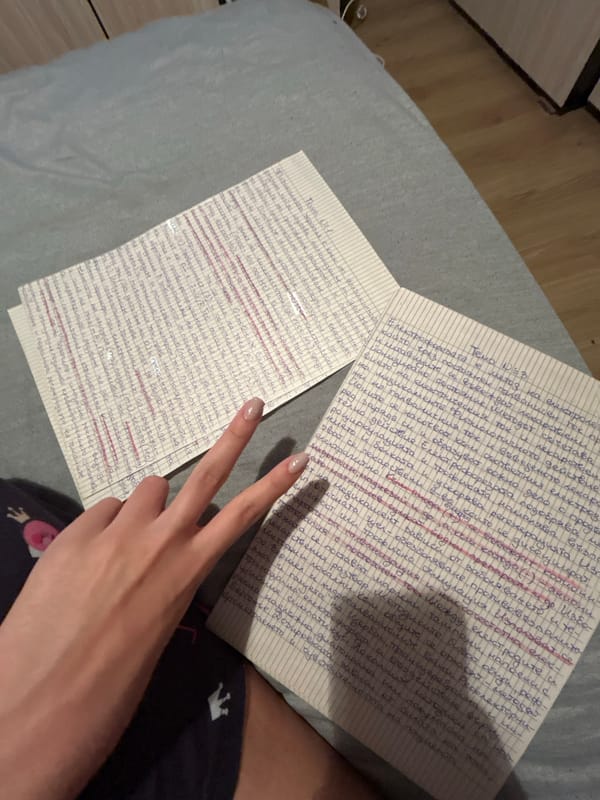 Person displays peace sign while holding handwritten notes on bed